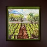 Small framed painting of vineyard rows running toward distant trees